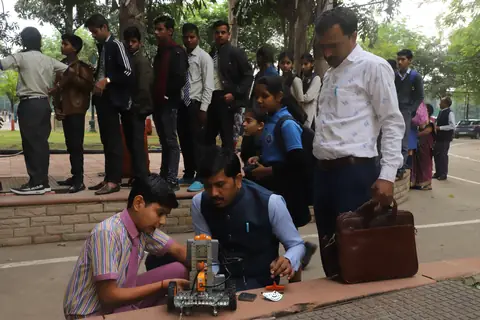 A student demonstrating a robot to a visitor at an outdoor expo
