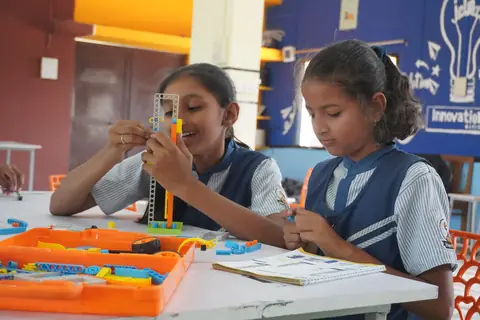 Two girls building a robot from a kit