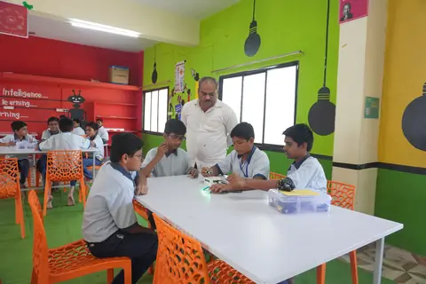 A teacher guiding groups of students across a bright, colourful lab