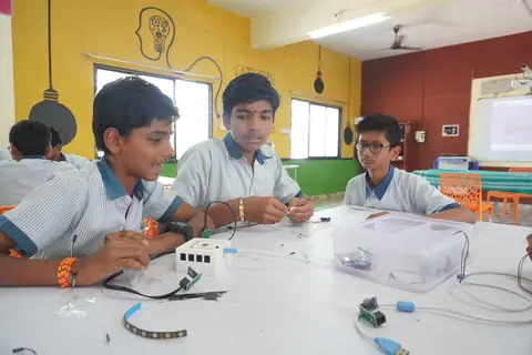 Three students assembling a circuit with sensors and cables