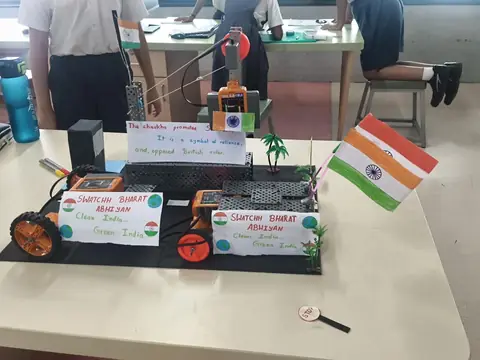 Student-built robot models with Swachh Bharat Abhiyan placards and an Indian flag