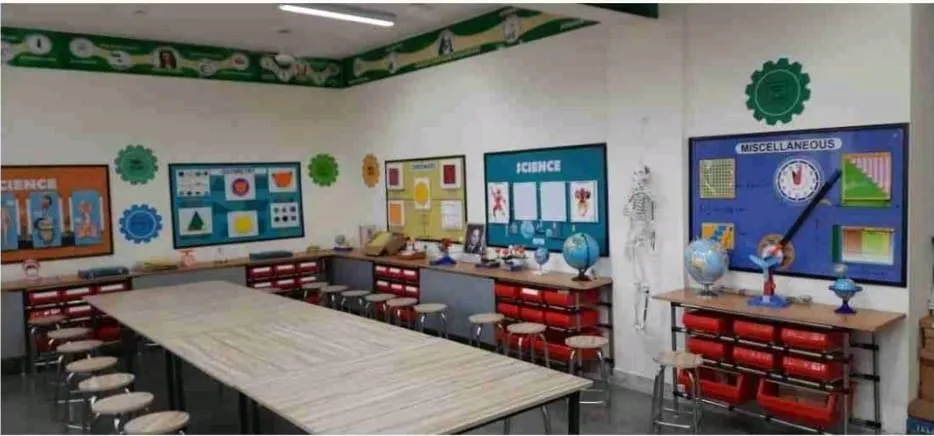 A science and maths lab with subject wall panels, models, a skeleton, globes and red storage bins along the walls